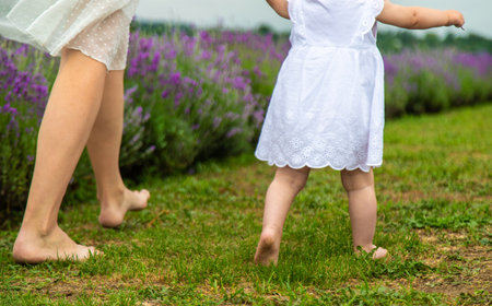 Mother and child's legs running on grass.の写真素材