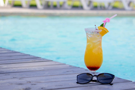 A nice cocktail, hat and sunglasses by the pool.