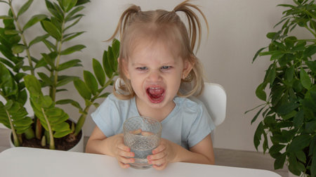 little girl drinks water from a glass. Selective focus.