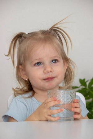 little girl drinks water from a glass. Selective focus.の写真素材