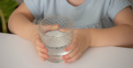 little girl drinks water from a glass. Selective focus.の写真素材