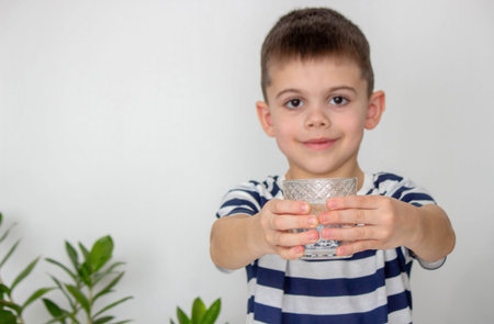 Boy drinking water from a glass. Selective focus.