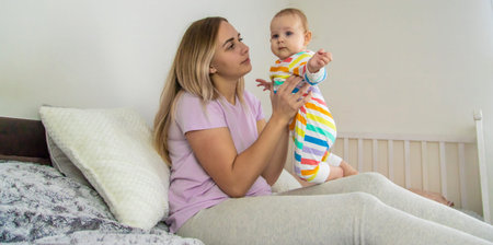 mother plays with baby on bed,hugs baby.happy childhood