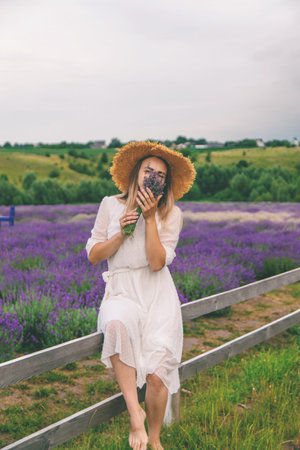 Woman in lavender field. Happy carefree woman in white dress and straw hat walking through lavender fieldの写真素材