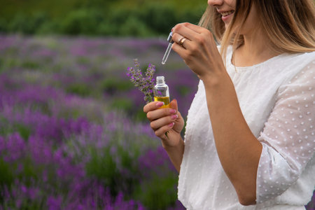 Woman in lavender field holding essential oil in her handsの写真素材