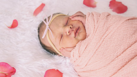 baby girl sleeping on white background and rose petals around.の写真素材