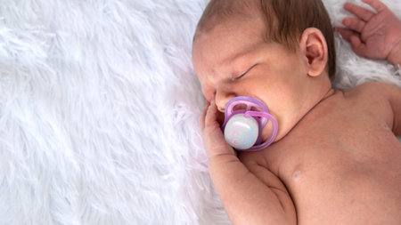 baby sleeping with a pacifier on a light background. pacifier, habit