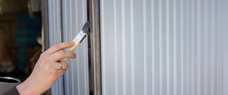 close-up of a man painting metal black with a brush.paintingの写真素材