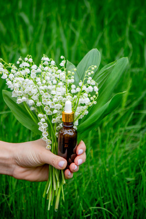 Glass bottle of lily of the valley essential oil with fresh flowersの写真素材
