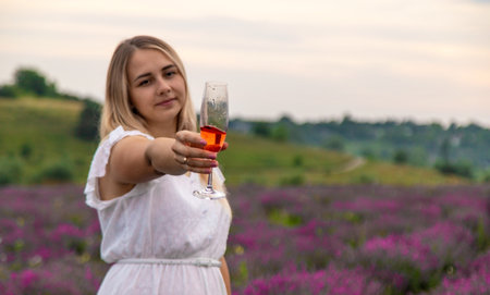 Woman in a white dress in a lavender field with a glass of wine. Vacation.の写真素材