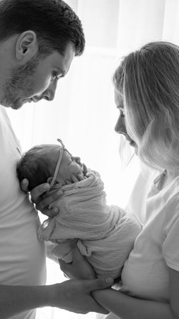 Young family, man and woman holding a baby in their arms. Newborn conceptの写真素材