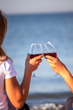 Two girls drinking wine by the sea.の写真素材