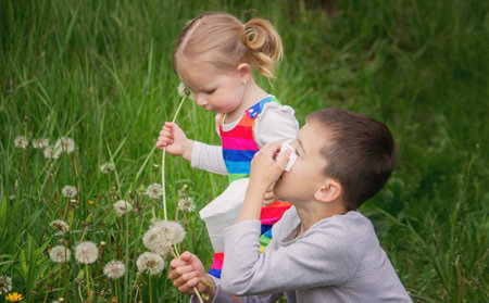 Blowing on a dandelion. Seasonal allergy in a child. Running noseの写真素材