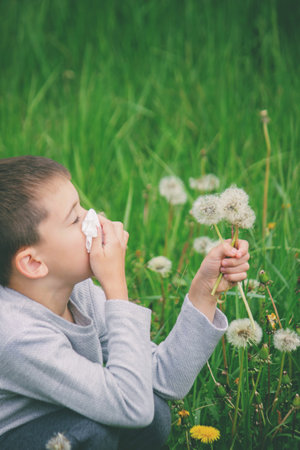 The boy has allergies. He is blowing on a dandelion.の写真素材