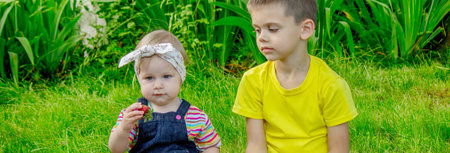 Children eating strawberries on a garden background. Selective focus.