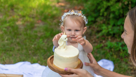 Little girl's first birthday. Mom holds cake. Celebrationの写真素材