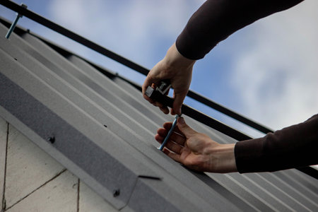 A man is installing solar panel mounts on the roof. Selective focus.の写真素材
