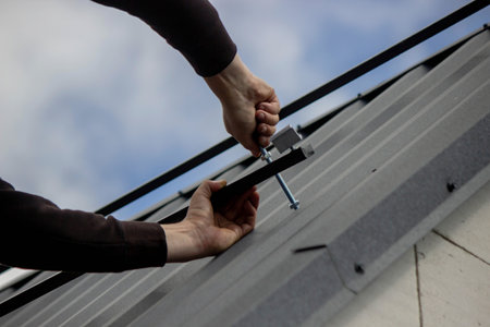 A man is installing solar panel mounts on the roof. Selective focus.の写真素材