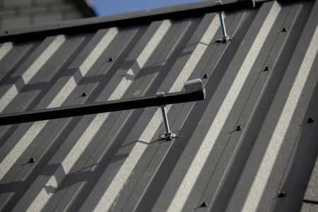 A man is installing solar panel mounts on the roof. Selective focus.の写真素材