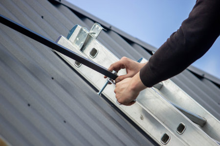 A man is installing solar panel mounts on the roof. Selective focus.の写真素材