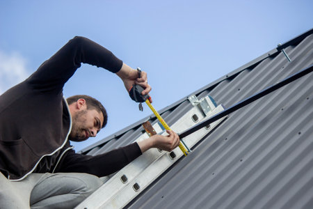 A man is installing solar panel mounts on the roof. Selective focus.の写真素材