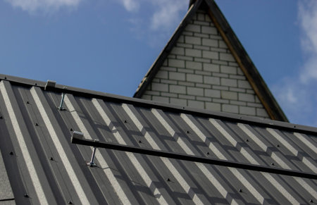 A man is installing solar panel mounts on the roof. Selective focus.の写真素材