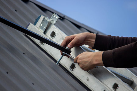 A man is installing solar panel mounts on the roof. Selective focus.
