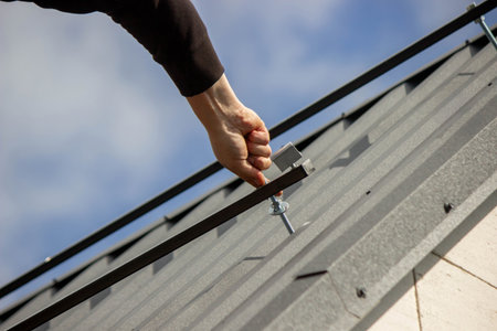 A man is installing solar panel mounts on the roof. Selective focus.の写真素材
