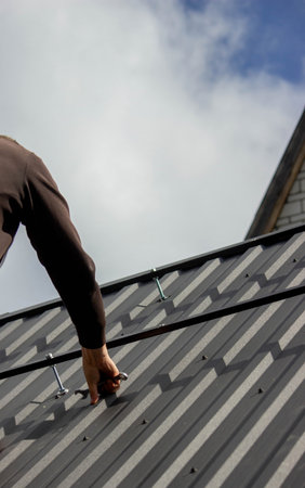 A man is installing solar panel mounts on the roof. Selective focus.の写真素材