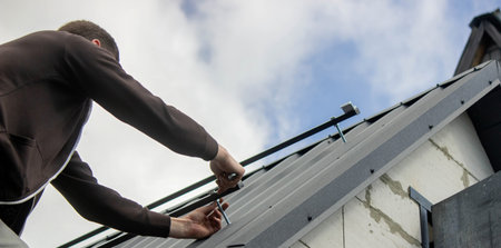A man is installing solar panel mounts on the roof. Selective focus.の写真素材