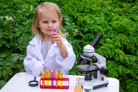 A little girl conducts experiments using test tubes, reagents, and a microscopeの写真素材