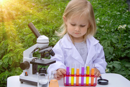 A little girl conducts experiments using test tubes, reagents, and a microscopeの写真素材
