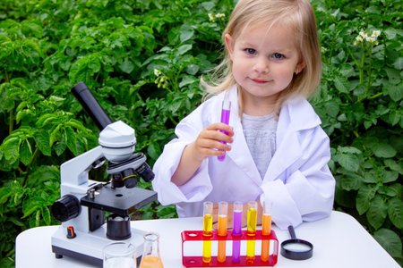 A little girl conducts experiments using test tubes, reagents, and a microscopeの写真素材