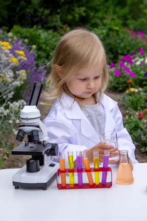A little girl conducts experiments using test tubes, reagents, and a microscopeの写真素材