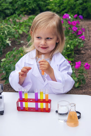 A little girl conducts experiments using test tubes, reagents, and a microscopeの写真素材