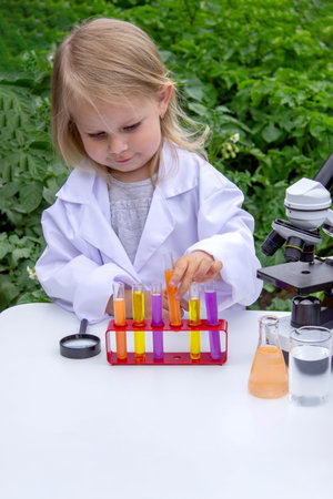 A little girl conducts experiments using test tubes, reagents, and a microscopeの写真素材