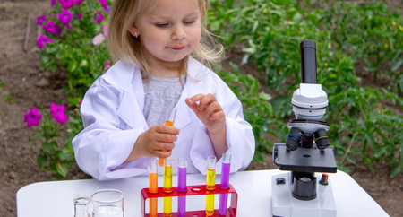 A little girl conducts experiments using test tubes, reagents, and a microscopeの写真素材