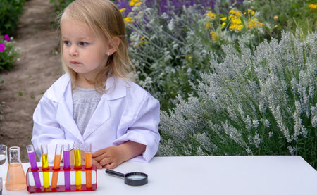 A little girl conducts experiments using test tubes, reagents, and a microscopeの写真素材