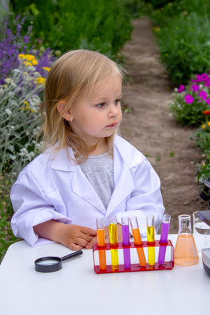 A little girl conducts experiments using test tubes, reagents, and a microscopeの写真素材