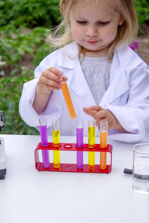A little girl conducts experiments using test tubes, reagents, and a microscopeの写真素材