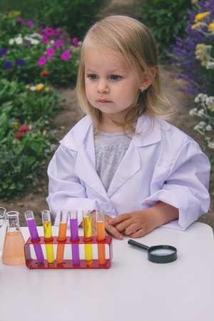 A little girl conducts experiments using test tubes, reagents, and a microscopeの写真素材