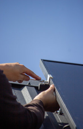 A man is installing solar panels on a roof. Selective focus.の写真素材