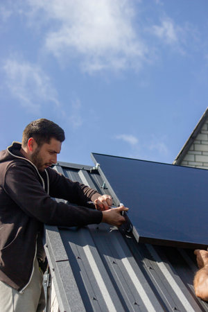 A man is installing solar panels on a roof. Selective focus.の写真素材