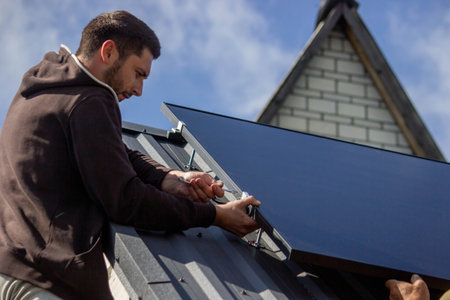A man is installing solar panels on a roof. Selective focus.の写真素材