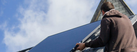 A man is installing solar panels on a roof. Selective focus.