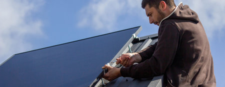 A man is installing solar panels on a roof. Selective focus.の写真素材