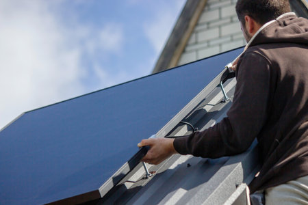 A man is installing solar panels on a roof. Selective focus.の写真素材