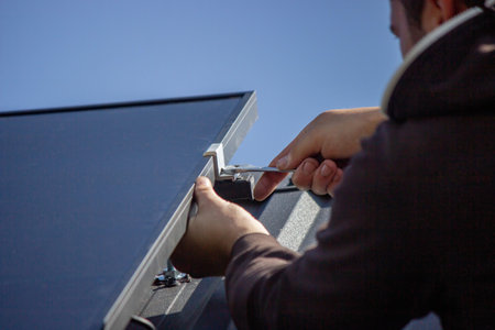 A man is installing solar panels on a roof. Selective focus.の写真素材
