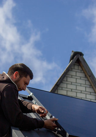 A man is installing solar panels on a roof. Selective focus.の写真素材