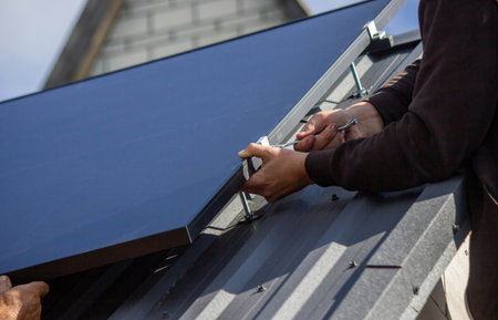 A man is installing solar panels on a roof. Selective focus.の写真素材